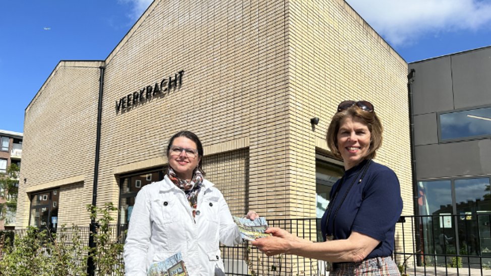 Veerkrachtdirecteur Atie van der Vlist neemt het straatspeurtochtboekje in ontvangst van comitévoorzitter Hélène de Bruine.
