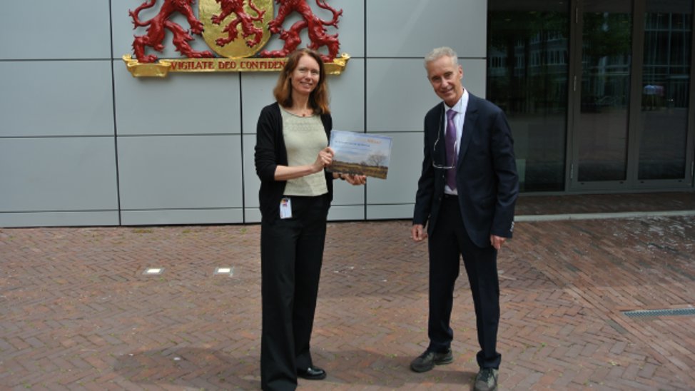 Dick Ooms overhandigt het rapport aan gedeputeerde Anne Koning.