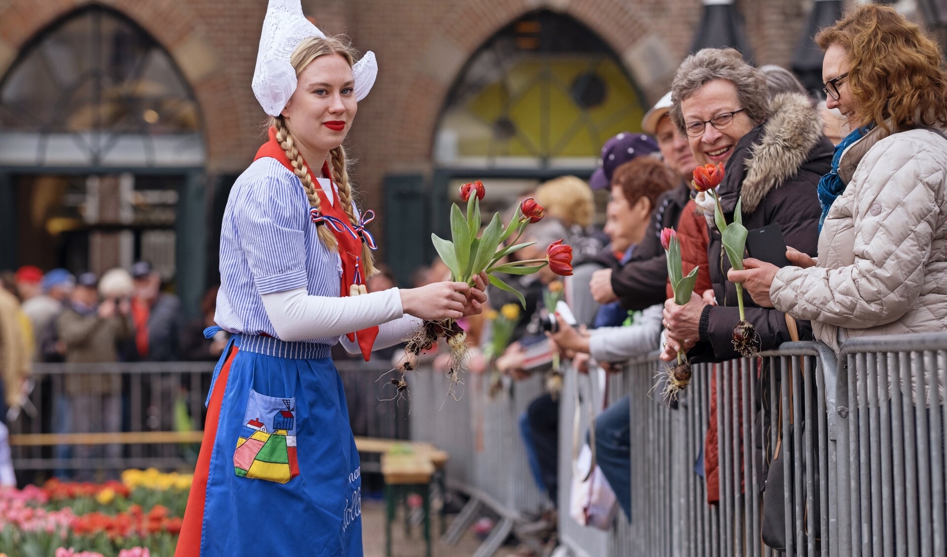 Kaasmeisjes delen tulpen uit aan bezoekers kaasmarkt. (Foto: aangeleverd)