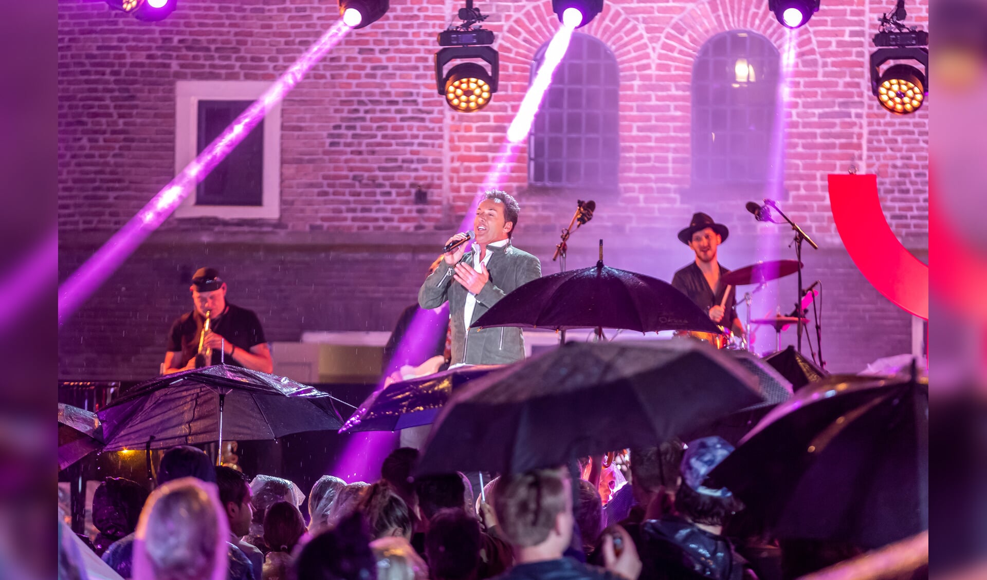 Boven de paraplu's treedt Gerard Joling op in 'Nederland staat op tegen kanker'. (Foto: Ed vd Pol)