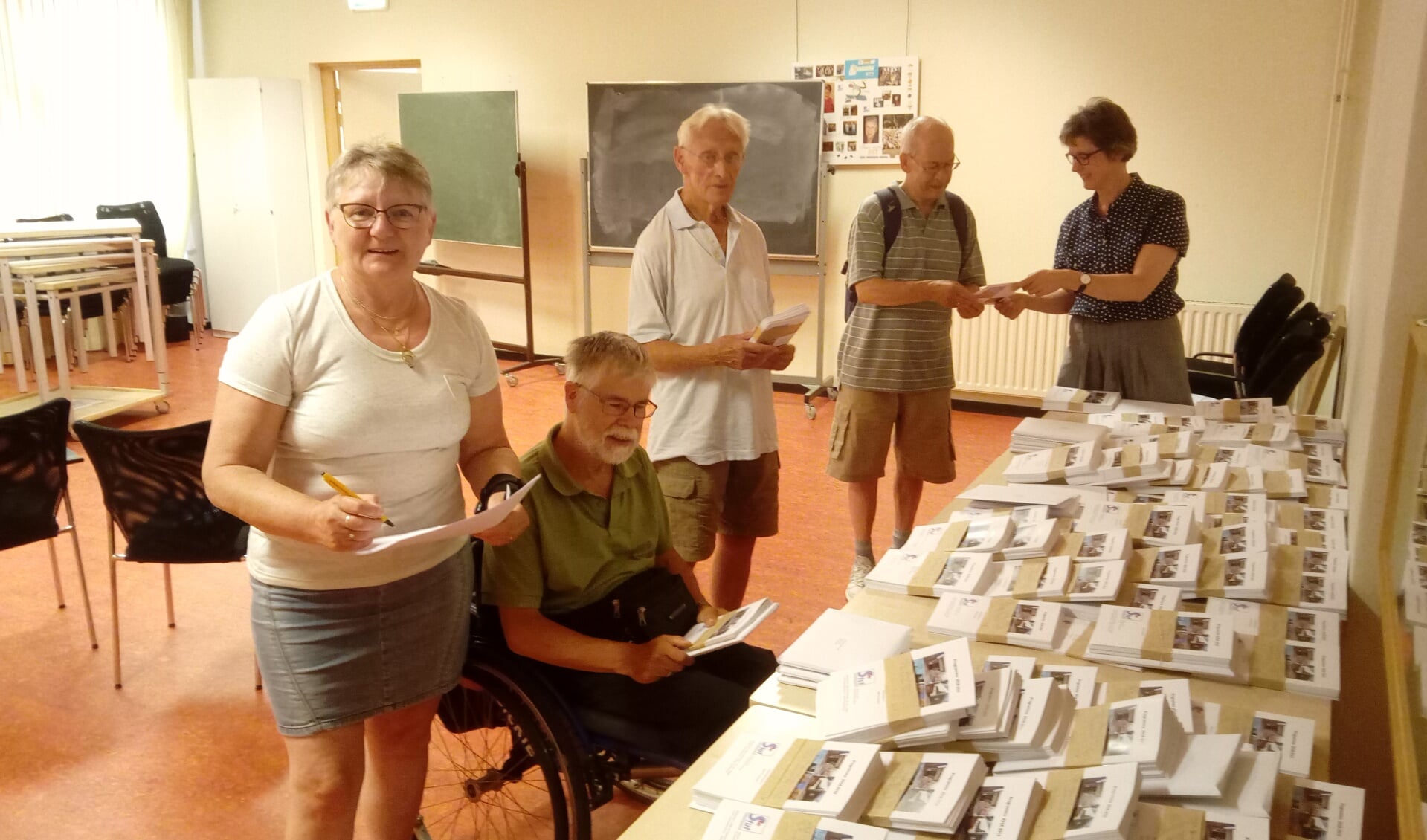 Coördinator Erna van Kempen (uiterst rechts) deelt de programmaboekjes uit aan vrijwilligers die de boekjes bezorgen. (Foto: Bos Media Services)