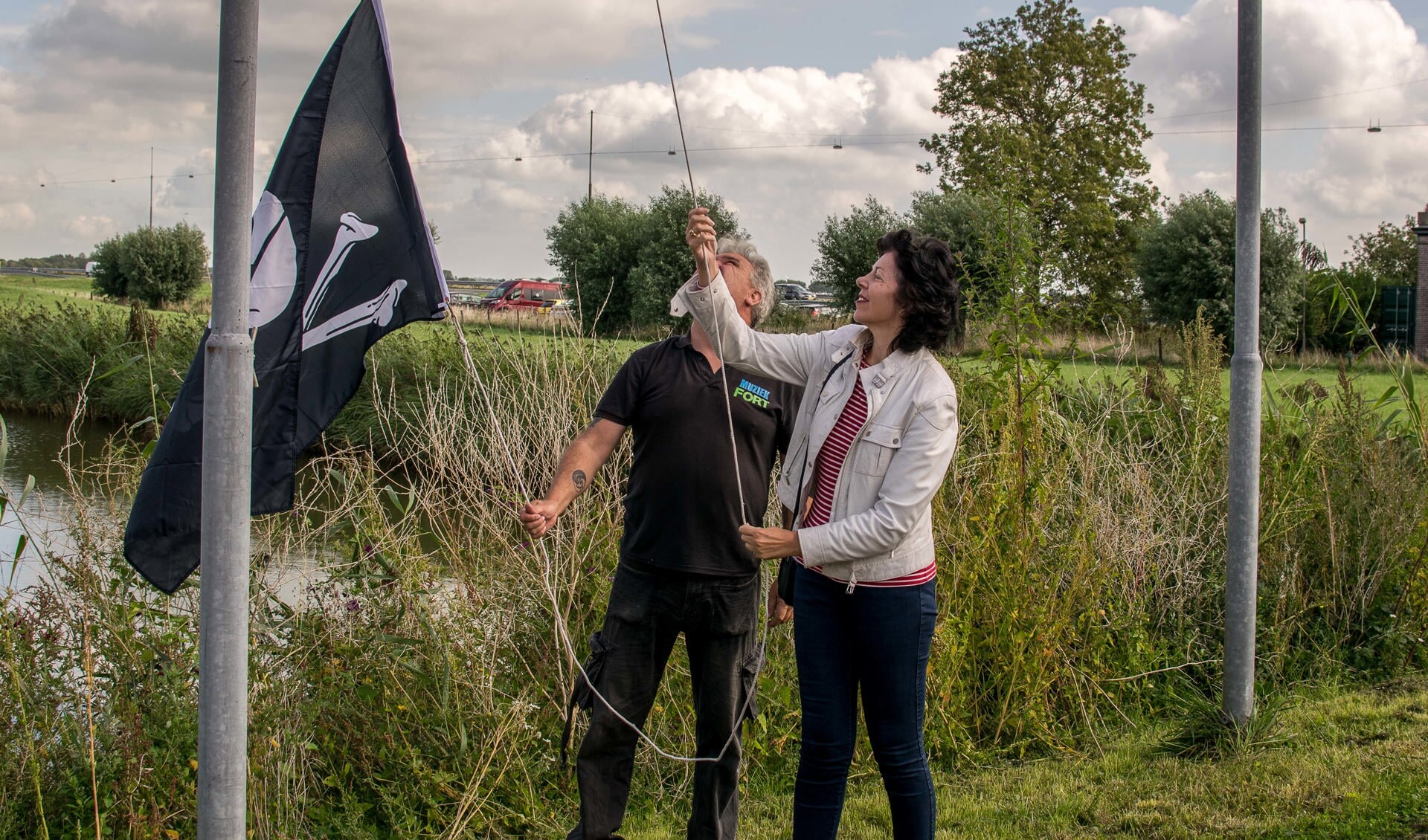 Wethouder Hanneke Niele helpt met het hijsen van de piratenvlag. (Foto: Aangeleverd)