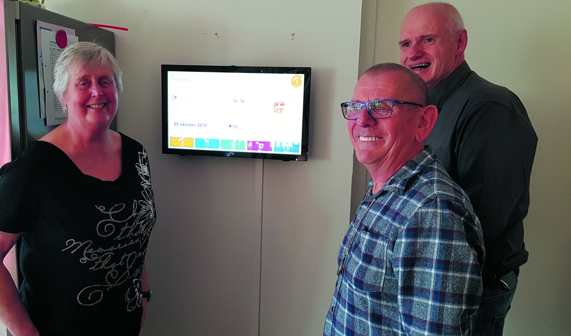 De bewoners Marjan, Gerrit en Pieter (vlnr) zijn inmiddels gewend aan het digitale bord. (foto Rodi Media)