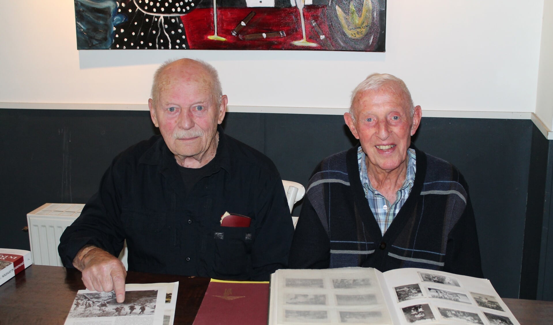 De heer Veldhoen en heer Stiemer laten foto's zien van vroeger. (Foto: Rodi Media/SZ) 