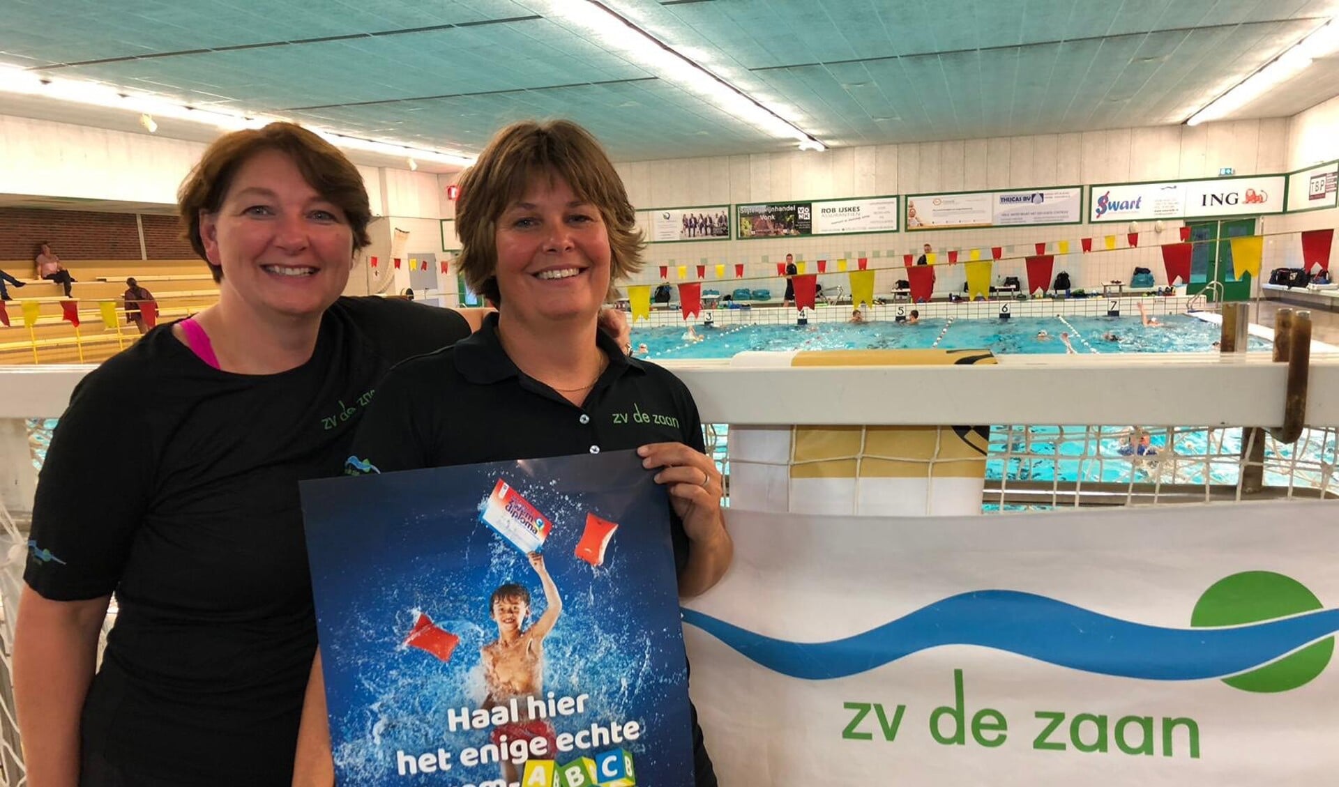 Judith Abcouwer (links) en Deborah de Lange (rechts) nemen de Licentie Nationale Zwemdiploma's in ontvangst. (Foto: ZV De Zaan)