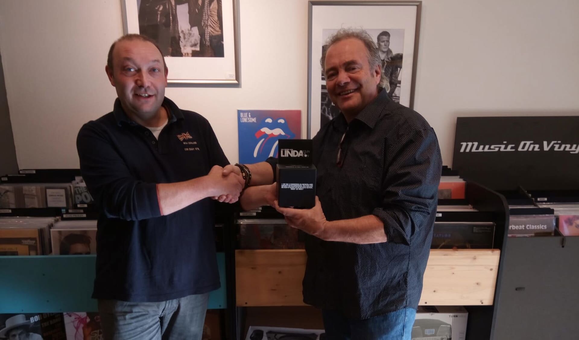 Frank Koning (rechts) reikt een donatiebox van de Linda Foundation uit aan ondernemer Joost Bart, eigenaar van de winkel bmm games n’ vinyl aan de Breestraat 140 te Beverwijk.