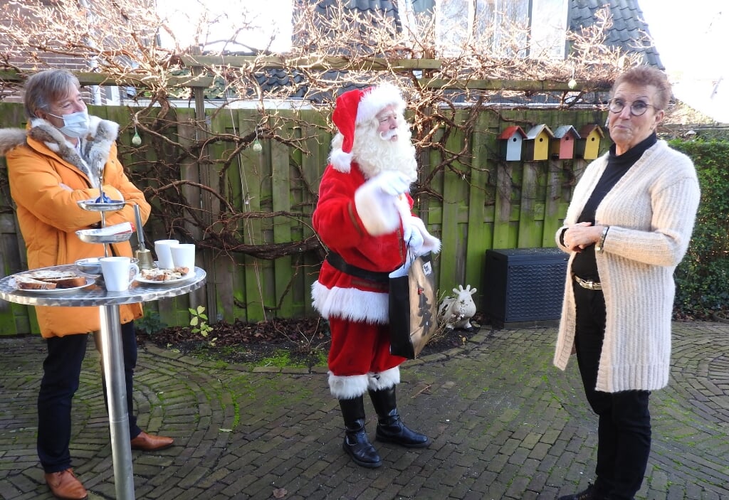 Kerstman, Marianne Vollers en voorzitter Leo van Schoonhoven met een verrassing.