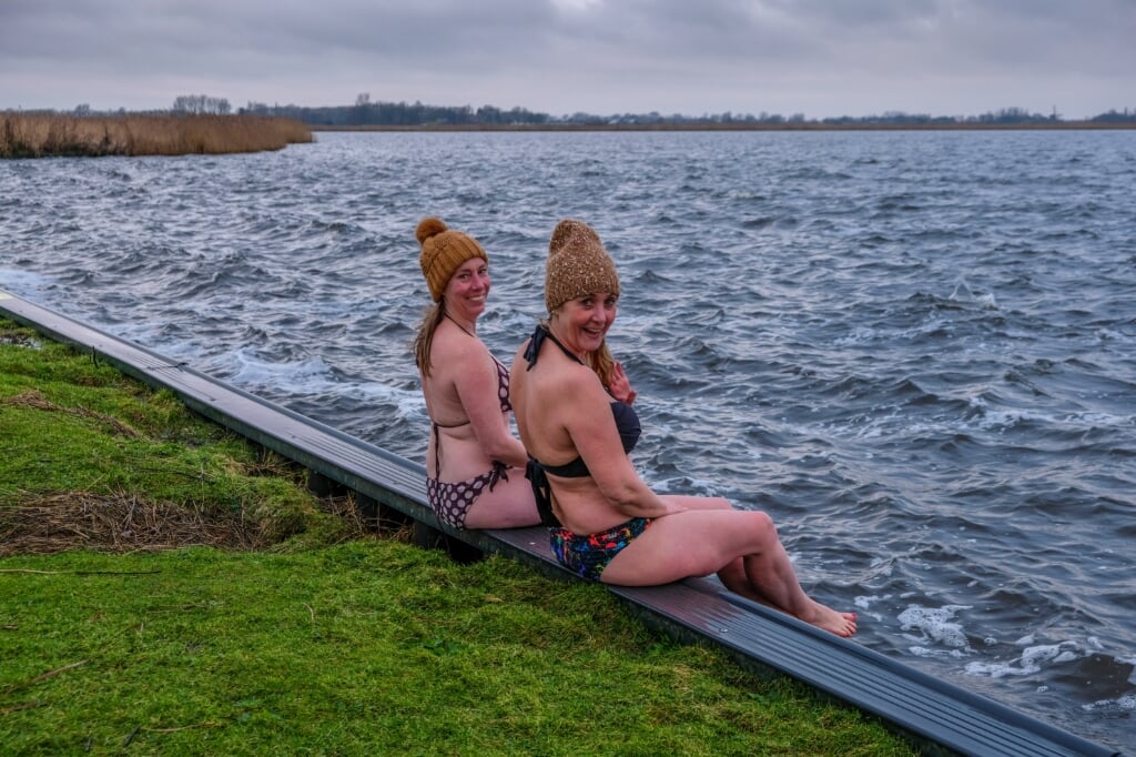 Elrieke Muller (l) en Yvette van der Does gereed voor een plons in het water bij een felle noordoostenwind en schuimkoppen op het water. 