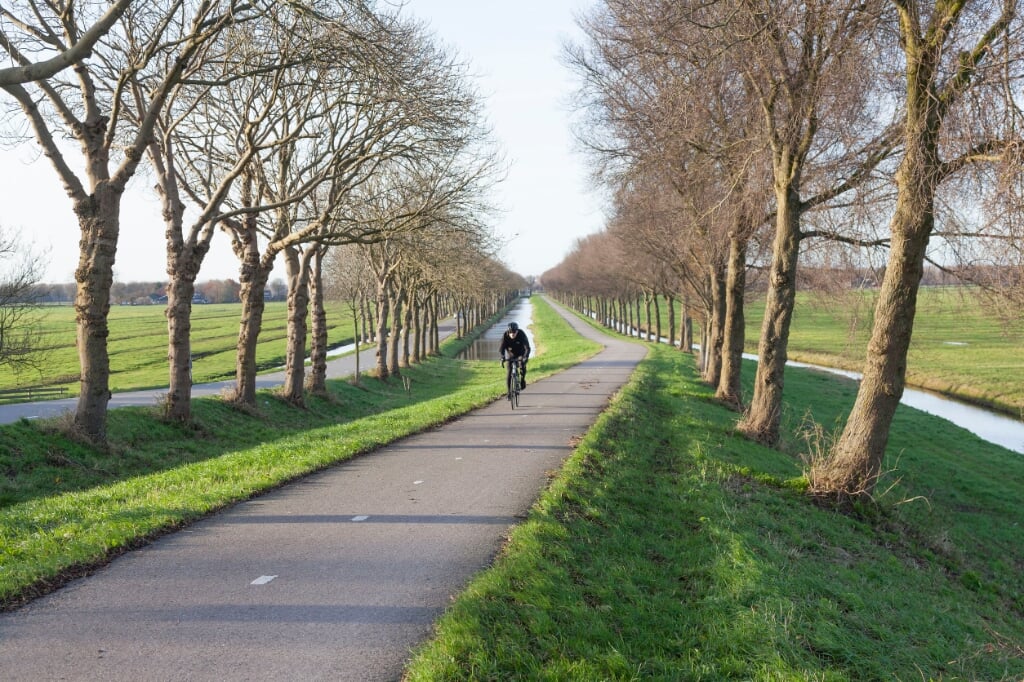Fietser klimt dijk van de polder Purmer ten noorden van Amsterdam in Nederland op fietspad