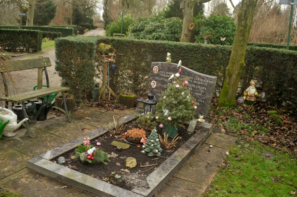 Een graf opgesierd met kerstversiering.