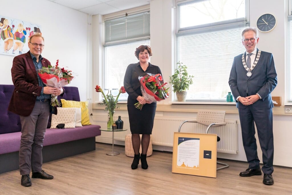 Burgemeester Don Bijl (rechts) reikt de Gouden Waarderingsspeld uit aan Frits Hamann (voorzitter bestuur) en Wendy Kok (coördinator inloophuis) van Wij | Allemaal