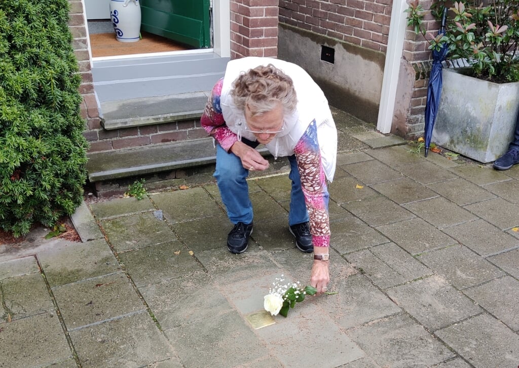 Mevrouw De Jong legt een roos bij de eerste steen. 