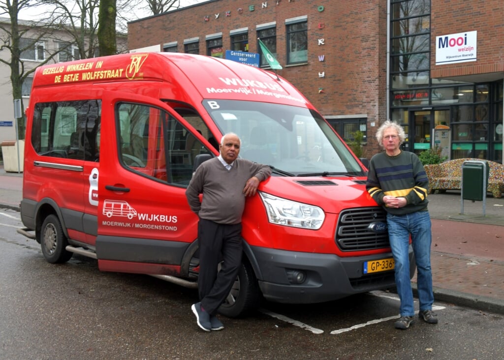 Voorzitter Soerin Narain (links) en secretaris Johan Apeldoorn bij de rode bussen waarmee stichting Wijkbus Zuid-West rijdt.