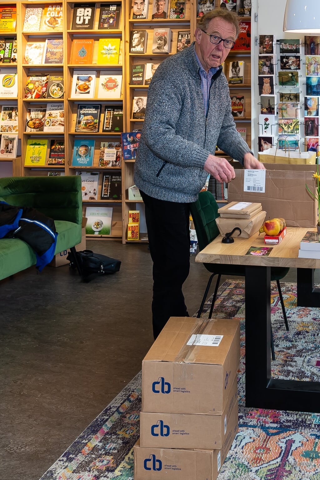 Cor Wouda pakt bestelde boeken in bij Het Leesteken en bezorgt ze bij de klanten. 