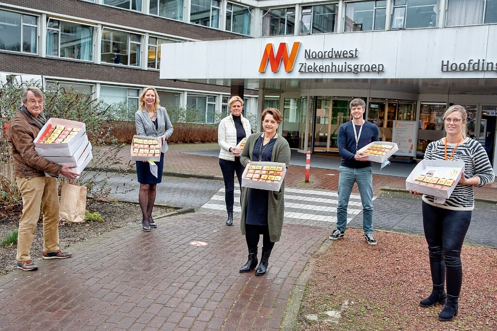 Kees van Straaten (links) en Tanja Schipper (midden achter) bieden namens ’t Praethuys tweehonderd potjes geluk aan voor kankerpatiënten.