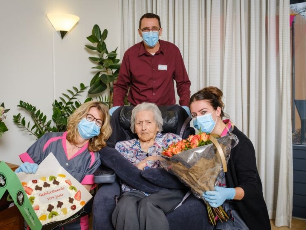 De 104 jaar oude Mia (m) wordt gefeliciteerd door het team van MagentaZorg.