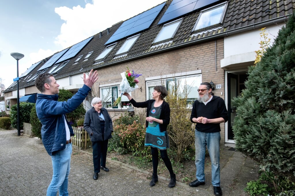 Bewoners ontvangen een bloemetje om te vieren dat de Jacob de Weijerlaan 100% gaat voor zonne-energie.