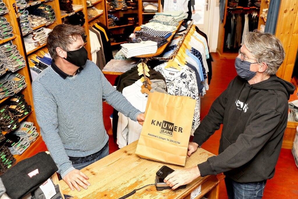 Mede-eigenaar Marcel van Knuwer Jeans, rekent af met een van de vaste klanten Max Hopmans.