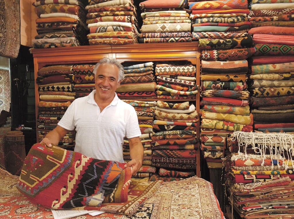 Davoud in zijn winkel vol Perzisch tapijten.