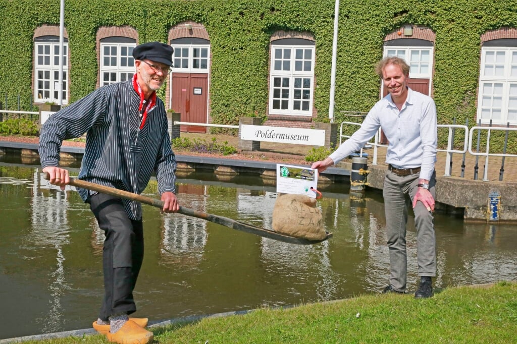 De 'oude' penningmeester Mart Kuiper (l) overhandigt symbolisch met een traditionele waterhozer de financiële bijdrage aan zijn opvolger Gert-Jan van Diepen.