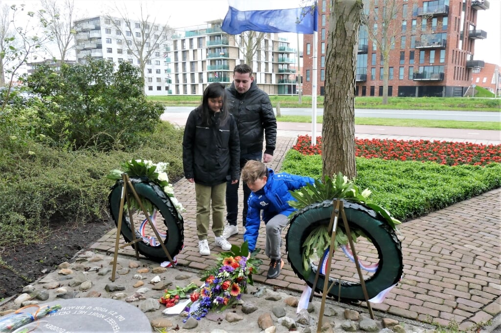 Sven Lekic en Kim Broekhuijsen van Trifolium leggen bloemen bij het monument aan de Jaagweg. Achter hen meester Dennis.