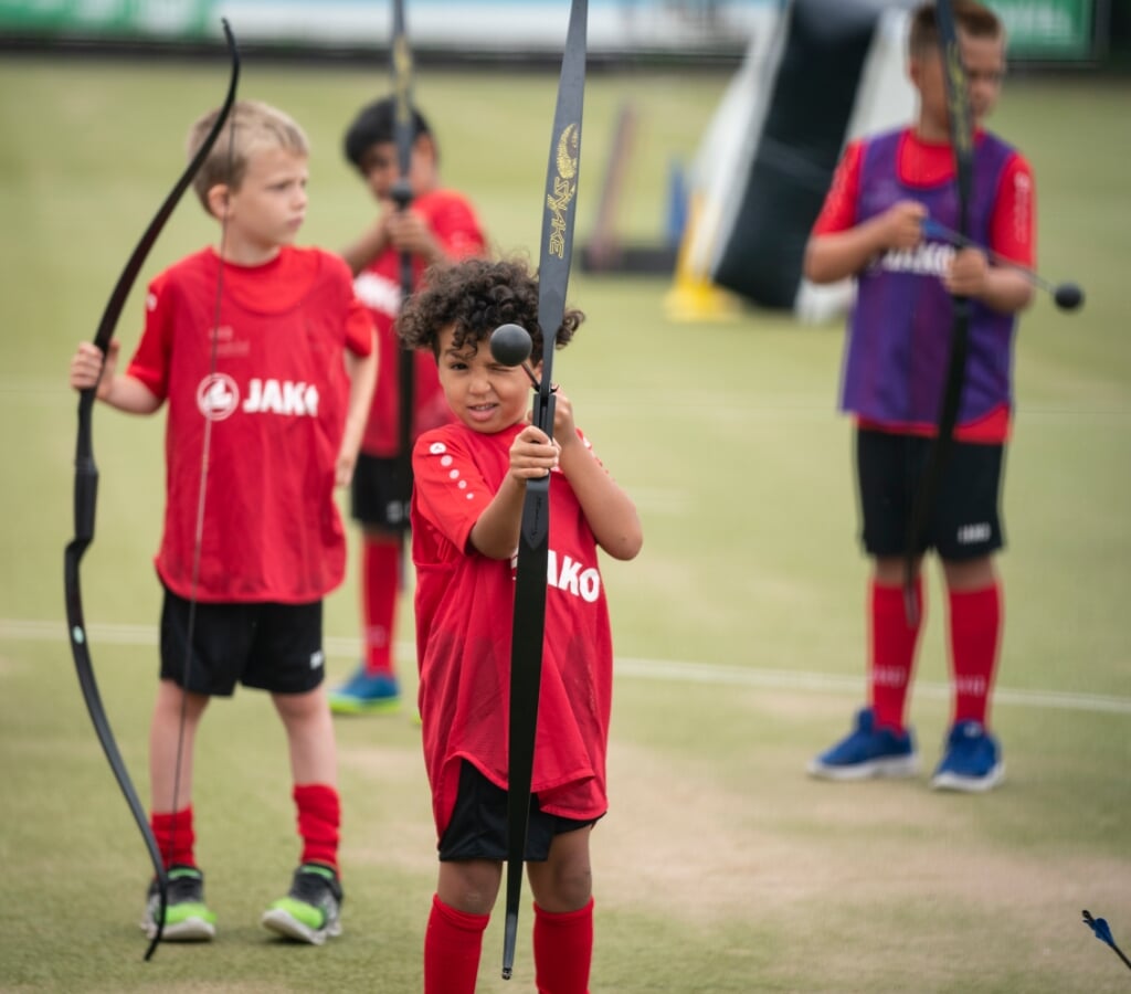 Kinderen spelen onder andere archery tag, een pijl- en boogspel tijdens het zomerkamp. 