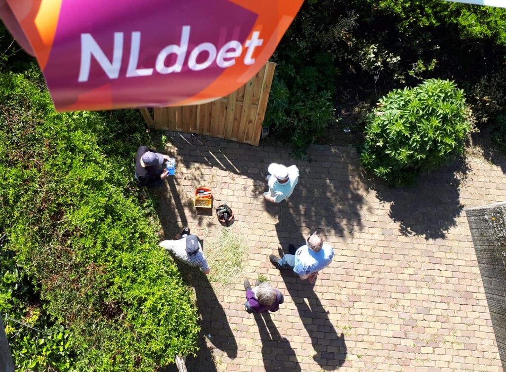 Vrijwilligers tijdens NLDoet actief met het aanpassen van de heg 
