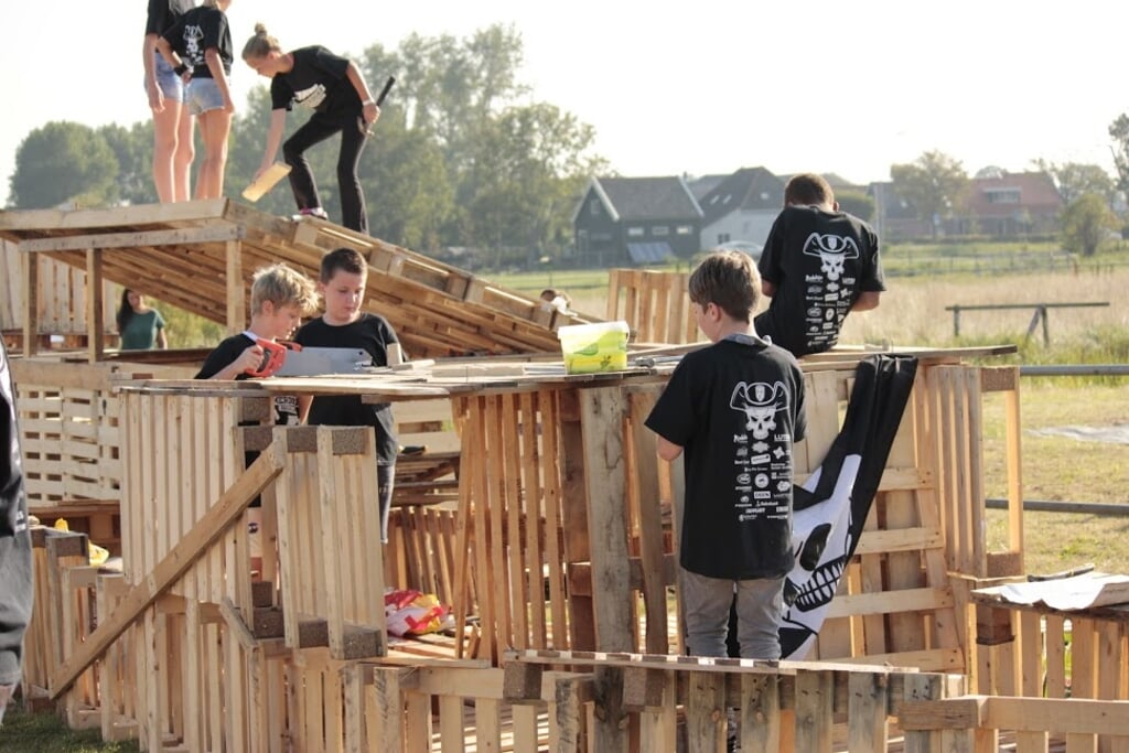 Jongeren zijn druk bezig met het bouwen van een dorp van pallets.