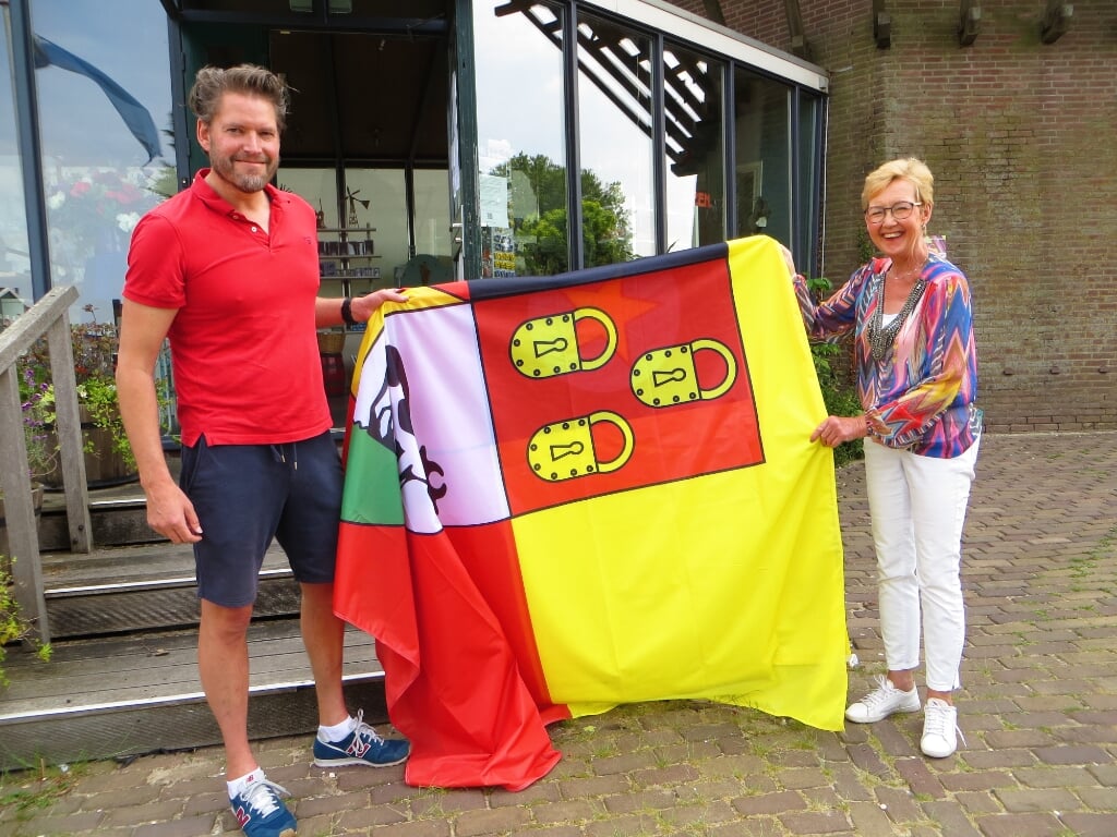 Atze uit Sloten en Jolanda Edema, pr-medewerkster Molen van Sloten, preseteren de nieuwe reuzenvlag die wappert langs de Molen van Sloten.