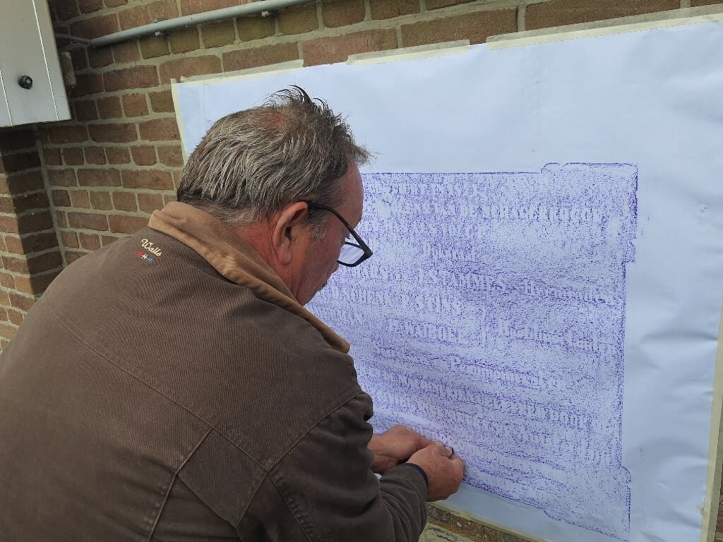 Ed Oosterhuis brengt door ‘rubben’ de tekst van de gevelsteen over op papier. 