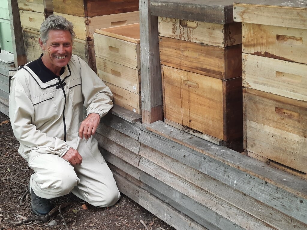 Jan Adrichem in vol ornaat voor de bijenkasten.