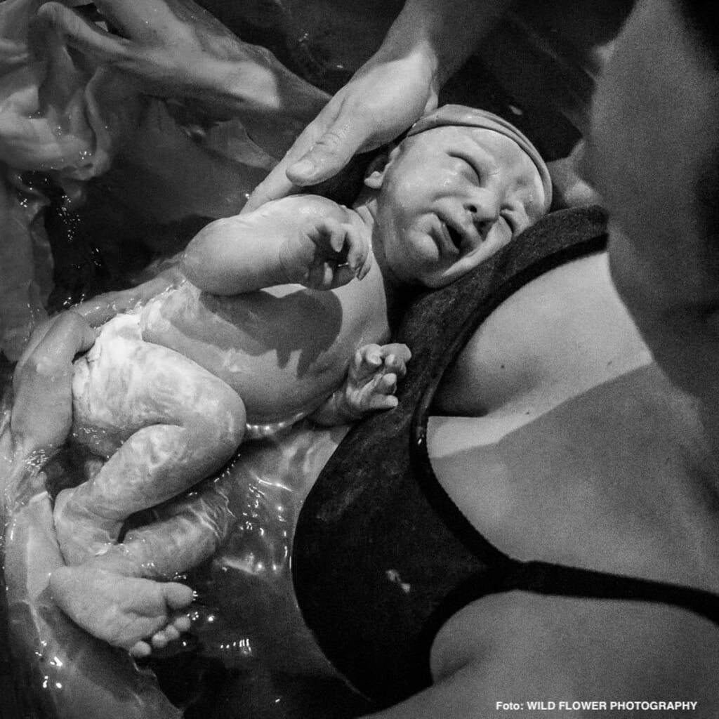 Vrouw bevalt van haar kind in bad.