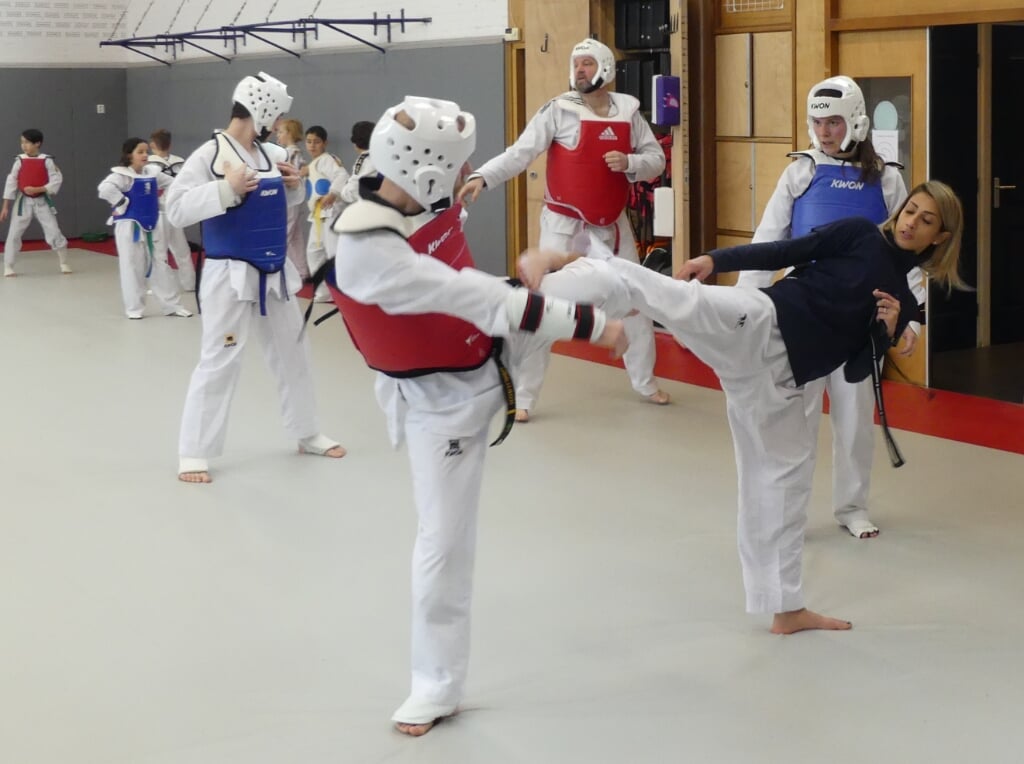 Dina Pouryounes (rechts) demonstreert een aanval-reactie combinatie met Purmerender Léon Möhlmann, Nancy Hasselt van Taekwondo Center Purmerend kijkt toe. 