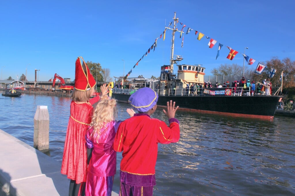 Vlnr Noor ((), Jailey (4) en Chelani (7) verwelkomen de pakjesboot van Sint en Pieten op de Gouwe in Boskoop.