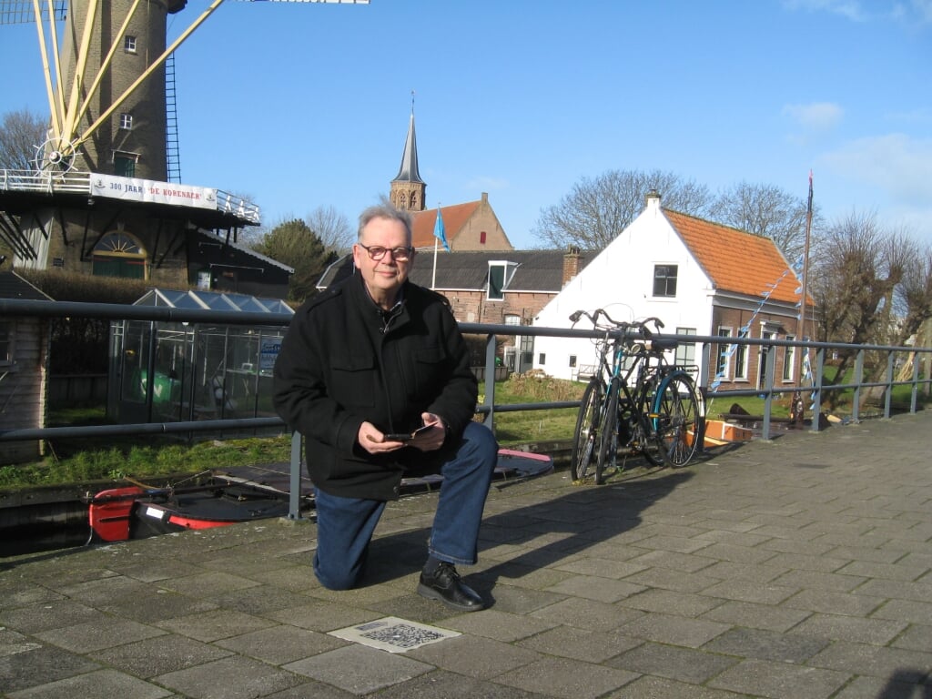 Hans Frankfort op zijn knieën bij één van de QR-codes van de Loosduinse Weetjes.