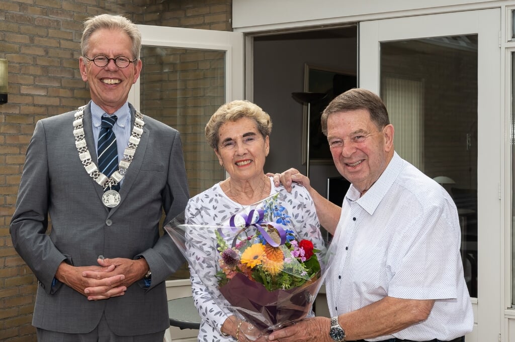 Jan Smit en Sonja Smit-van Gompel worden door burgemeester Don Bijl in de bloemen gezet.