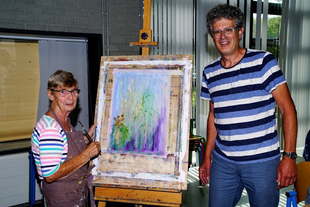 Ria de Groot en Hans Verbeek bij een schilderij van Ria. Naast schilderijen doen ook andere disciplines mee met de wedstrijd. 