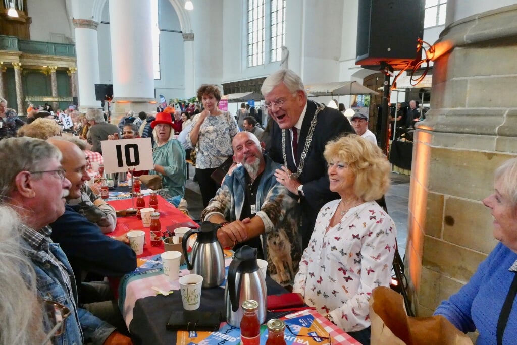 Burgemeester Jan van Zanen bij het tafeltje met bewoners van Leischenveen-Ypenburg.