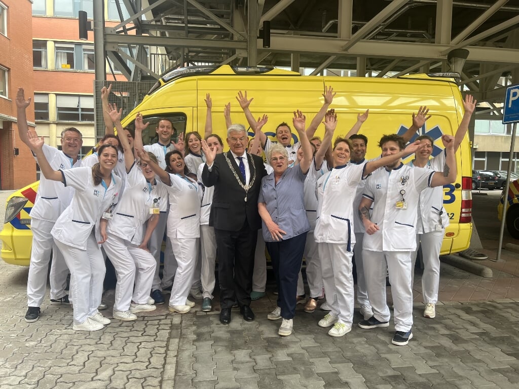 Burgemeester Jan van Zanen gaat op de foto met de zorgmedewerkers.
