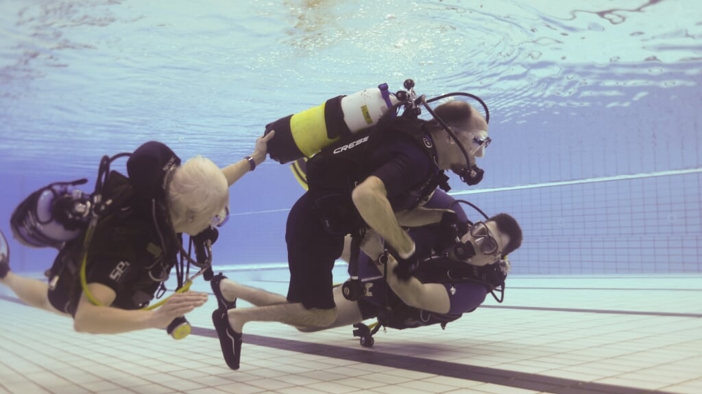 Instructeurs helpen een persoon met een handicap tijdens het duiken.