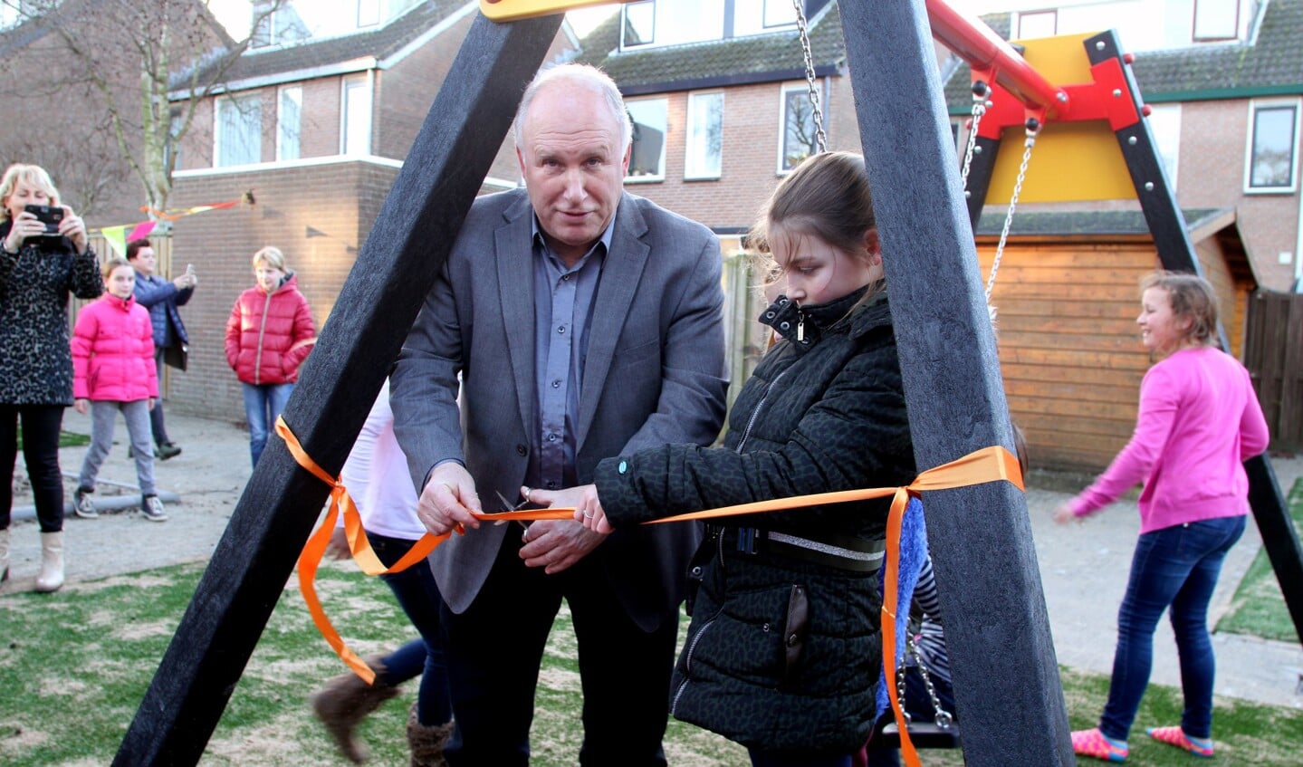 De wethouder knipt het lint, samen met een van de buurtkinderen door.