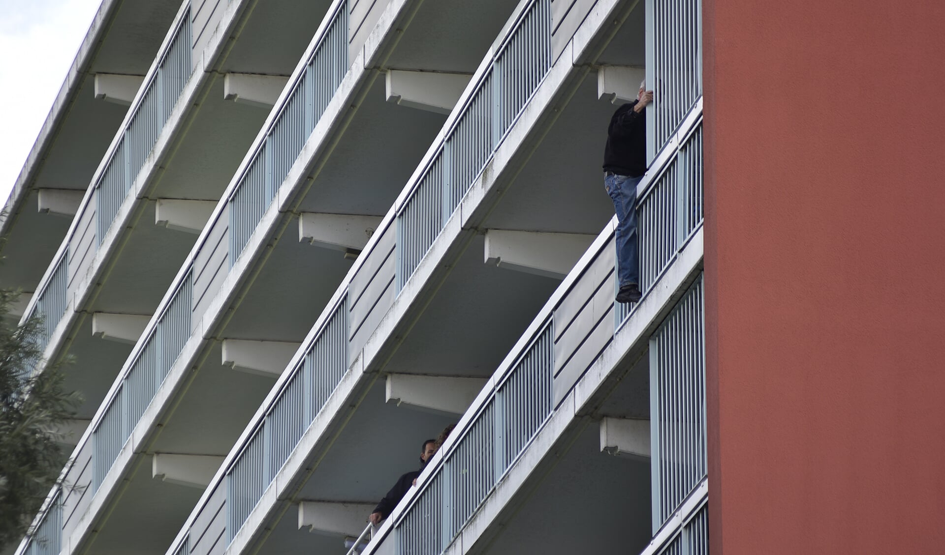 Hulpdiensten proberen de man te overreden naar de veilige kant van het balkon te komen. (Foto: René Bakker)
