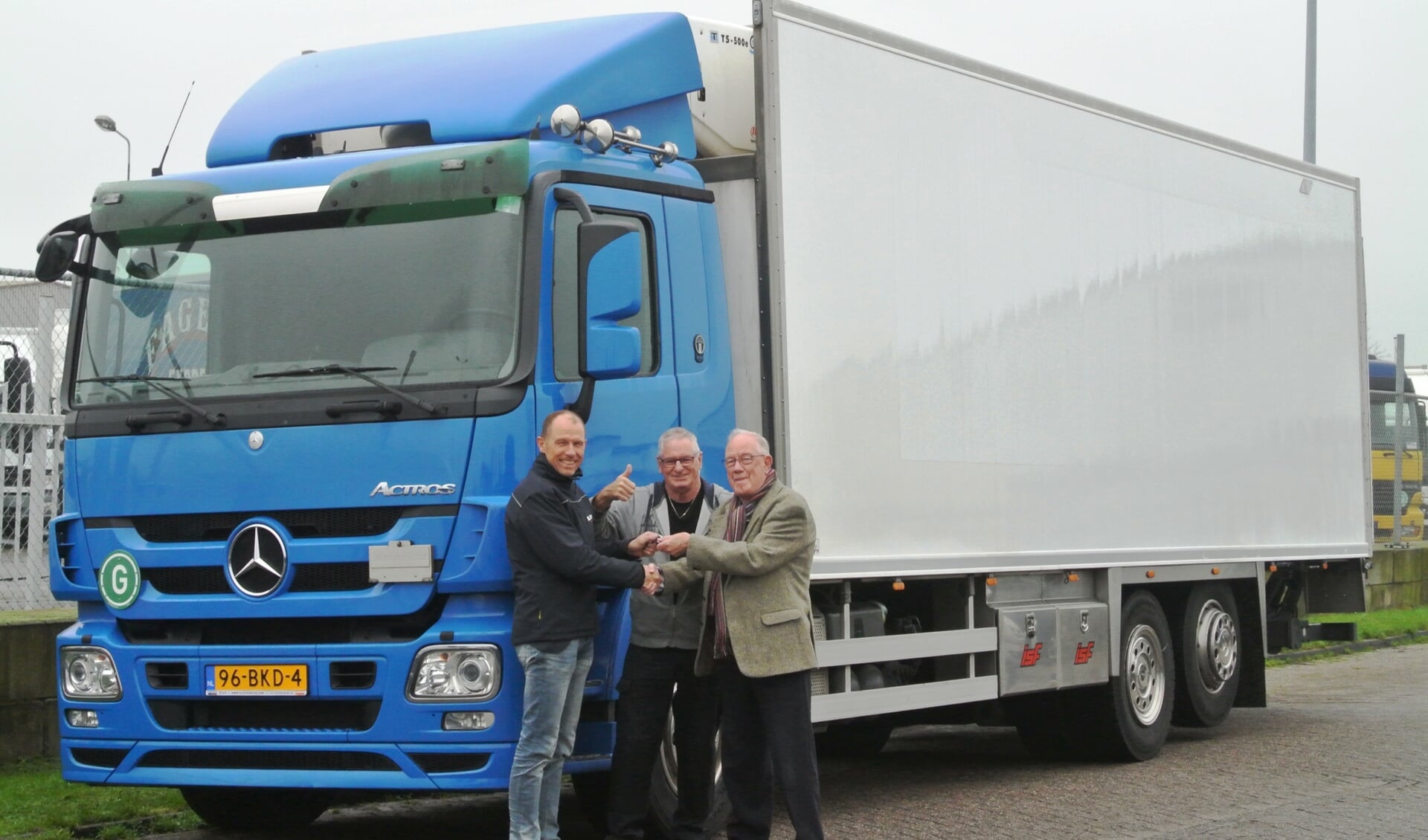 Lachende gezichten bij de overhandiging van de vrachtwagen aan Voedselbank-chauffeur Arie Burger (m.) en bestuurslid Gerrit van Buuren (r.) 
