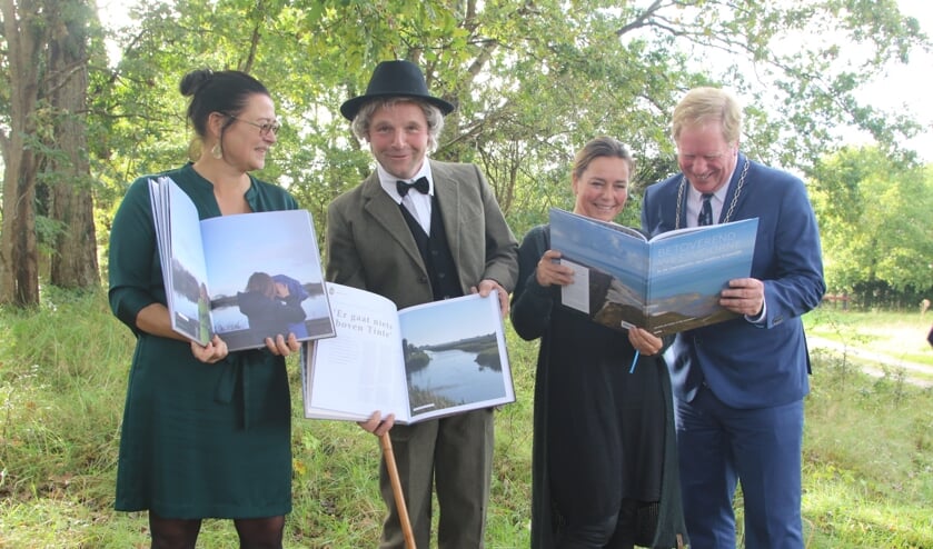 Bert Poot (tweede van links) als Jacobus Craandijk, en de samenstellers Marieke de Ruijter, Kim Grootjans en burgemeester Peter de Jong, bladeren exemplaren van het boek 'Betoverend Westvoorne' door. (Foto: Wil van Balen).