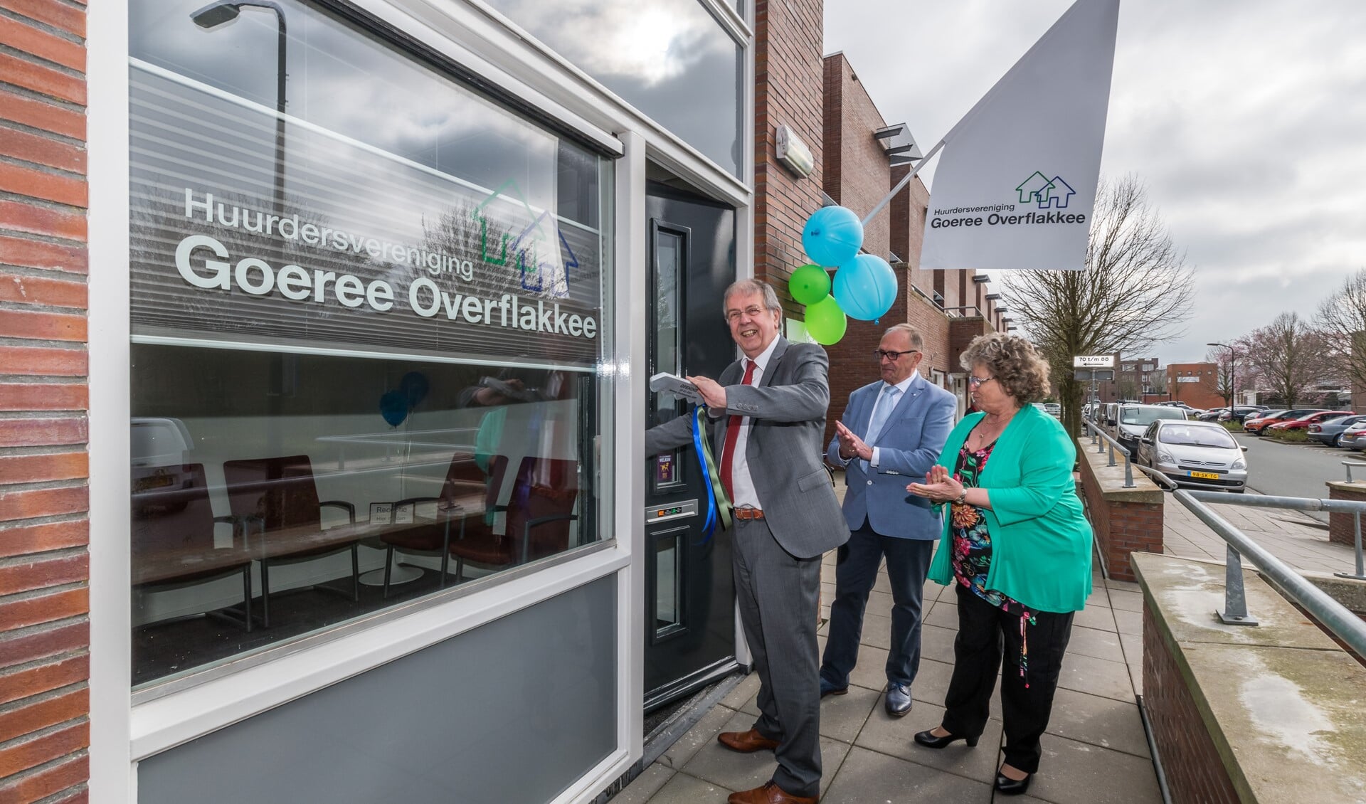 Onder het toeziend oog van voorzitter Maarten van der Klooster en penningmeester Wil Noteboom opent Simon van Nieuwaal de deur van het nieuwe kantoorpand van huurdersvereniging Goeree-Overflakkee.