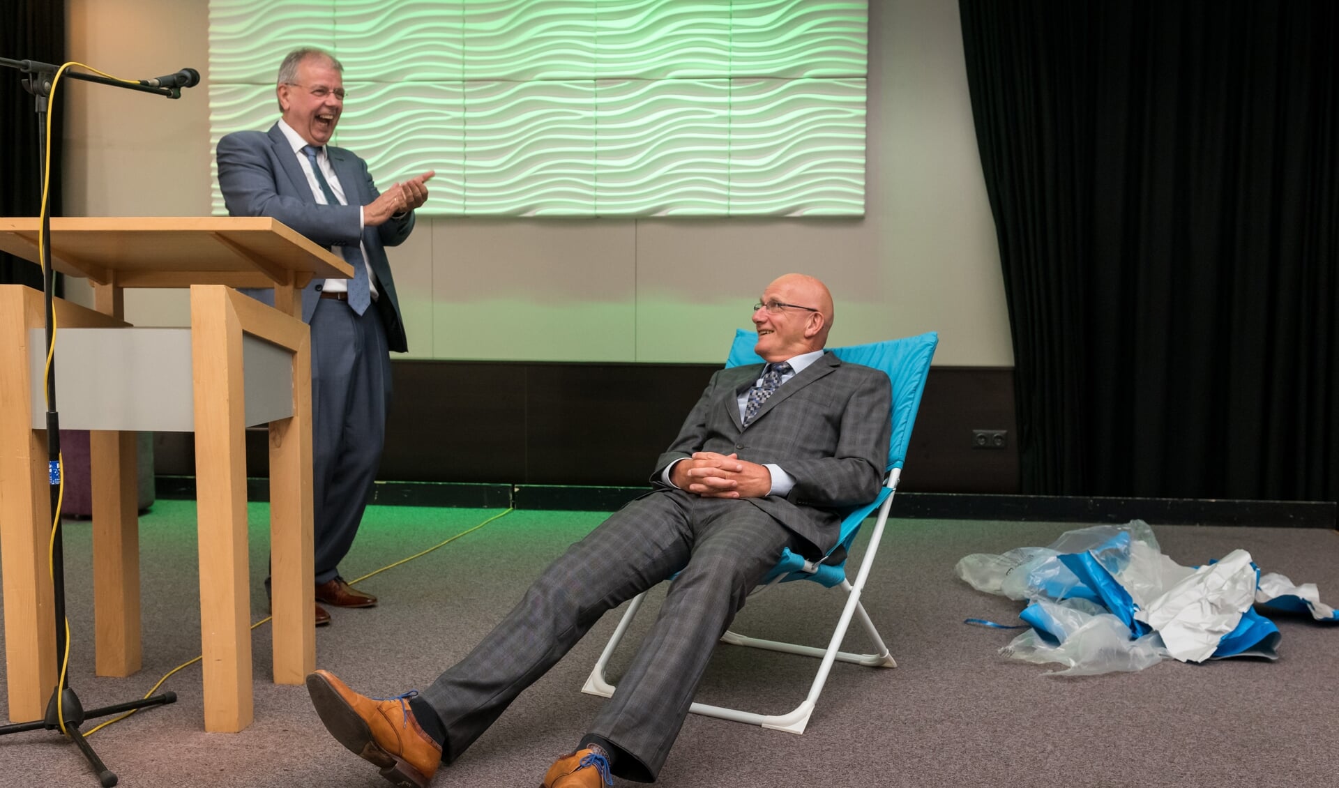 Twee scheidende directeuren van woningbouwverenigingen. Simon van Nieuwaal schonk Gert-Jan van der Valk het symbool van rust: de luie stoel.