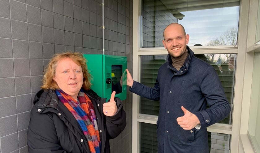 Anja van der Sijde (De Zes Kernen) en wethouder Struijk bij de AED in Abbenbroek.