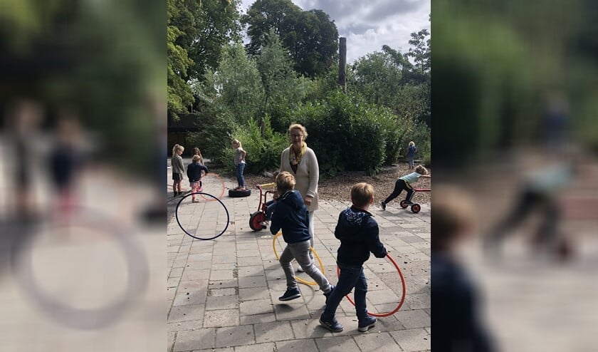 Juf Marjon tussen de kinderen op het schoolplein