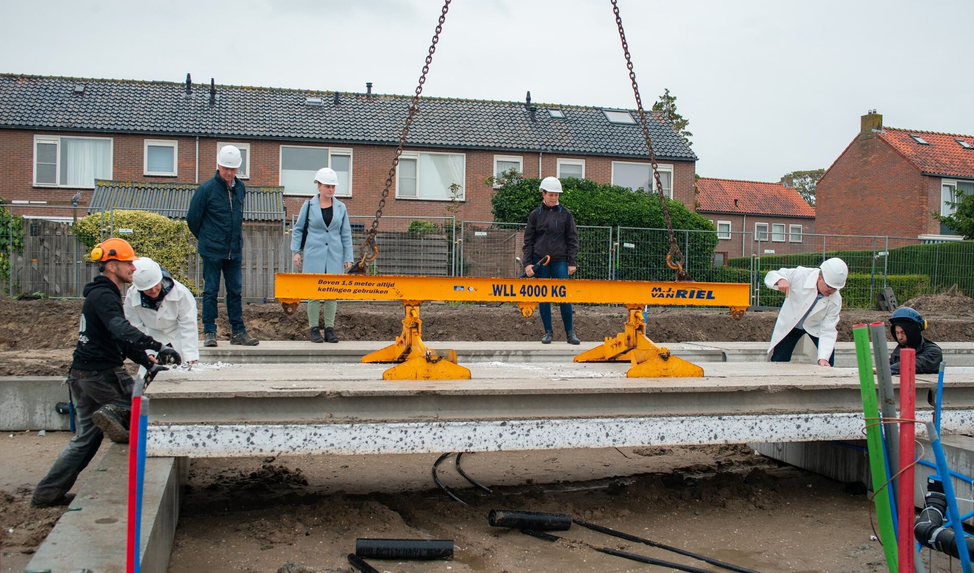 Wethouder Henk de Graad legt samen met hoofd Woonbedrijf Bronia Vermaas het laatste vloerelement van de begane grond van sociale huurwoningen aan de Hoogvlietlaan/Kolpapad in Rockanje