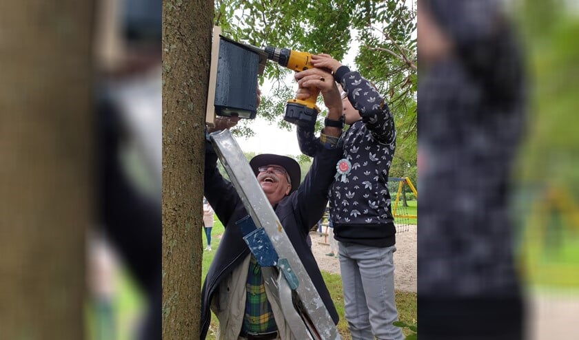 Djévano mocht meneer Wim helpen bij het ophangen van het vogelhuisje.